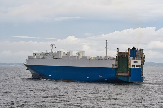 Vehicle carrier RO-RO cargo ship underway on open water under cloudy skies, broadside view