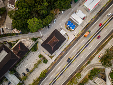 Aerial view of a highway with vehicles passing by next to a rest area featuring buildings with dark roofs, electric vehicle charging stations, and parking spaces in Salatiga, Central Java, Indonesia.
