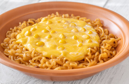 Cheesy Korean ramen with sweet corn and creamy melted cheese in terracotta bowl