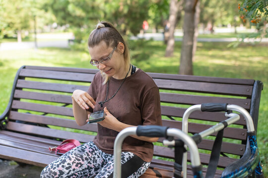 A Caucasian woman with cerebral palsy sits on a park bench.