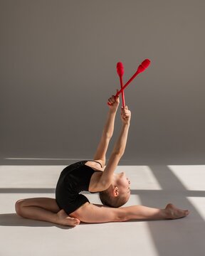 Little gymnast posing with clubs on white background. 