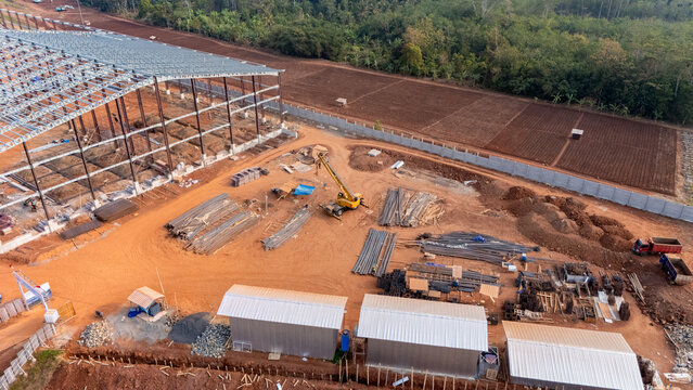 Aerial view of Kawasan Industri Terpadu Batang construction site, featuring a steel warehouse frame, mobile crane, materials, and site offices in Kecamatan Gringsing, Jawa Tengah, Indonesia.