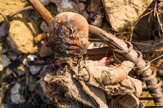 View of a damaged and dirty doll lying amidst debris, rocks, and wooden sticks near the shore of Lake Varna, Varna, Bulgaria.