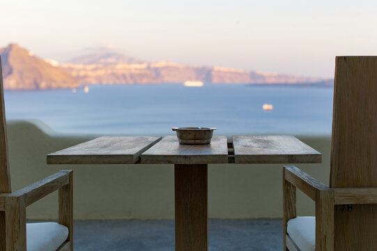 Wooden table and chairs overlooking the sea in Santorini