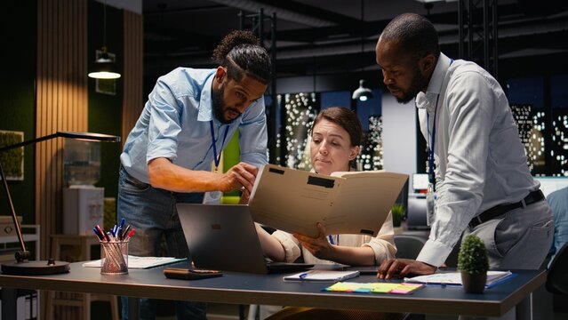 Multiethnic team collabor in a modern office workspace at night brainstorming ideas for a business project while associates document data and build a strategic action plan to achieve shared goals.