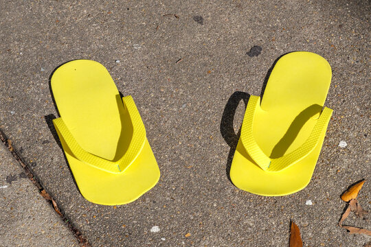 Pair of Yellow Disposable Flip Flops on a Sidewalk in New Orleans, LA, USA 