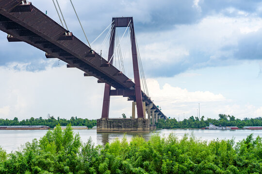 Wide View of the Hale Boggs Bridge over the Mississippi River with Tugboat and Barges Blurred in the Background