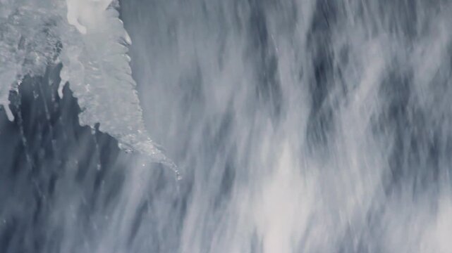 Melting icicle edge waterfall. Closeup frozen winter river stream cascading.