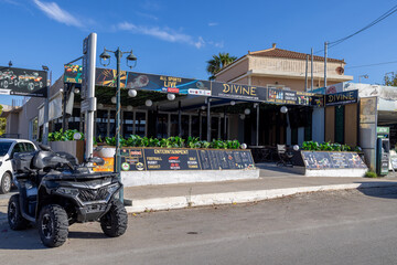 Obraz premium Kalamaki, Zakynthos Greece, 1st September 2026: Divine Cocktails and Entertainment Bar frontage with sports advertising outdoor seating menu boards plants and a quad bike outside