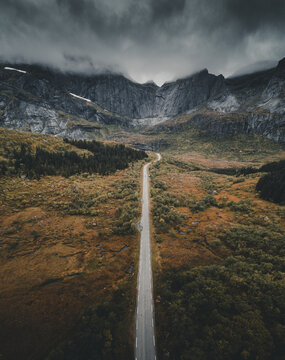 Aerial view of the Batman wall mountain range with a long road stretching through the autumn landscape in Ramberg, Nordland, Norway.
