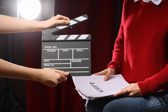 Film production and movie making, clapperboard used by assistant director on set with actor holding script for audition or rehearsal in studio