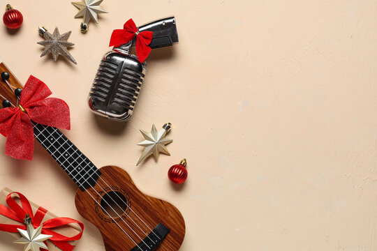 Christmas music and holiday entertainment concept, vintage microphone and ukulele with red bows and festive ornaments on a beige textured background