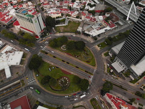 Aerial view of Glorieta Stampede featuring a circular intersection with lush green landscaping, fountains, and surrounding urban buildings in Guadalajara, Jalisco, Mexico.
