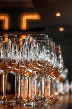 Empty stemware arranged beneath warm lights. Overlapping glass bowls and stems stand on a counter with amber shapes in the blurred background.