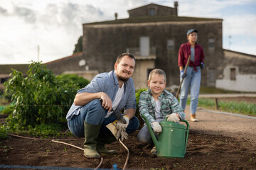 Obraz premium Farmer with son plant semen in cultivated land. Process of growing organically healthy vegetables and herbs on the farm. Season for planting seeds in the garden