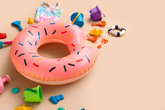 Summer vacation and travel planning, donut pool float with beach toys and swimwear for family holiday leisure on a soft beige background