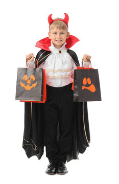 Little boy dressed for Halloween with gift bags on white background