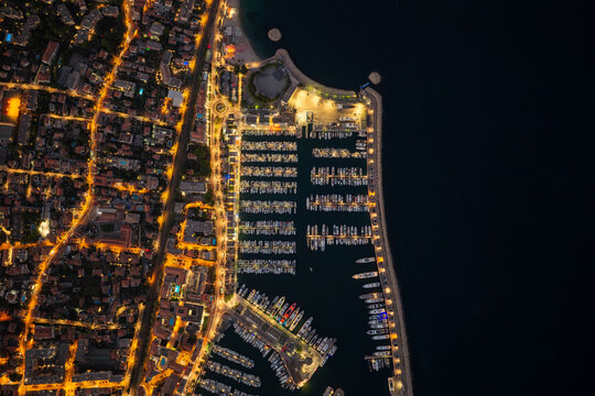 Aerial view of the illuminated Port Vauban marina at night, with yachts docked in rows, surrounded by glowing city streets. Antibes, Provence-Alpes-Cote d'Azur, France.