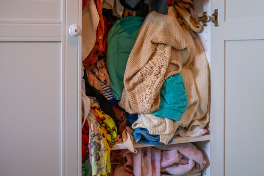 overcrowded wardrobe packed with clothes hangers, excess garments limited space, messy storage, decluttering, overconsumption lifestyle hoarding behavior accumulation, organization mental overload