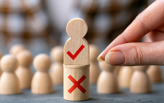 Human resources recruitment and candidate selection. Woman hand picking chosen wooden figure with check mark over rejected ones.