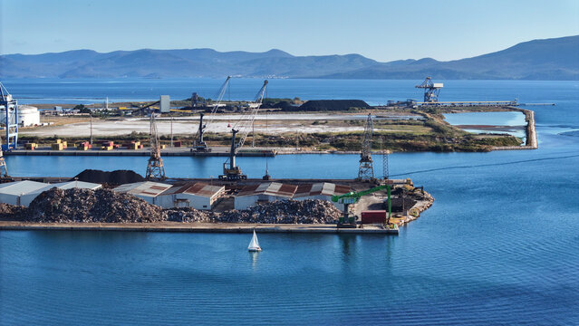 Aerial view of Port of Ploce with industrial cranes, shipping containers, and a small sailboat on the water under a clear blue sky in Croatia.