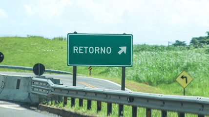 Green return route sign with right arrow beside a highway guardrail © photochamie