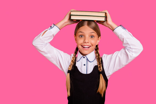 Close-up portrait of her she nice attractive lovely charming cute cheerful cheery playful pre-teen girl holding on head book class course isolated over bright vivid shine orange background