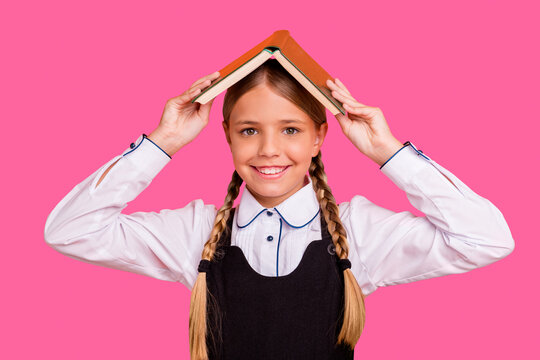 Close-up portrait of her she nice attractive confident cheerful cheery pre-teen girl holding over head academic book first 1 September fooling isolated over bright vivid shine orange background