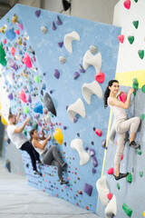 Obraz premium Athletic young woman practicing rock climbing on climbing wall..