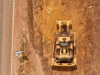 Aerial Top View of Bulldozer During Earthworks Beside Rural Road Construction Site © Aleksandar