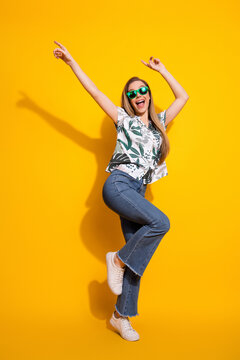 Lovely young woman in trendy attire posing against vibrant yellow background exuding energy and charm