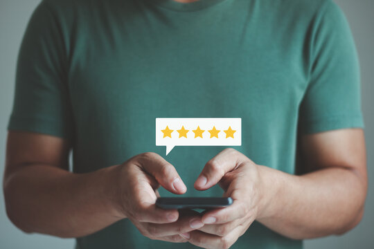 Customer satisfaction concept with five star rating on smartphone. Hand holding mobile phone showing online review, feedback, user experience, service quality, digital marketing, business reputation.