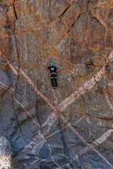 Athletic rock climbers scaling a high vertical crag marked by striking geometric white mineral dykes in an arid canyon landscape. © Valentin