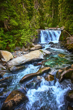 Waterfall and Stream Flowing Through Forest in Lush Mountain Landscape
