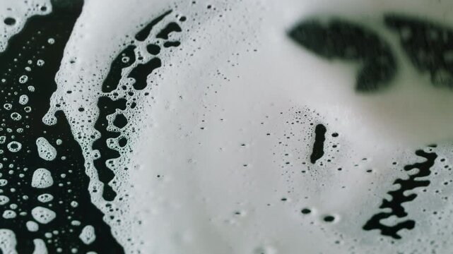 Cleaning foam on black glass, washing dirty window with sponge and soap suds, glass cleaning service and household chores close up macro