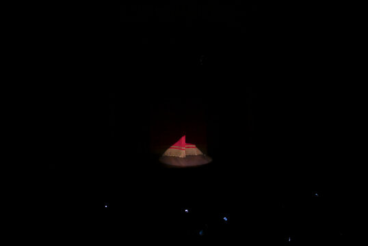 spotlight focused on red stage curtain fringe in dark theater, minimalist theatrical stage background, dramatic spotlight performing arts concept