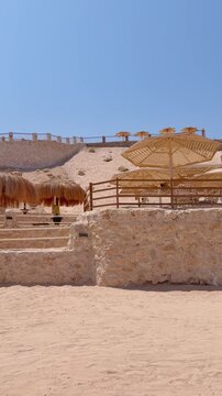 Sunny desert oasis with woven parasols and palm against clear blue sky Egypt. Hurghada