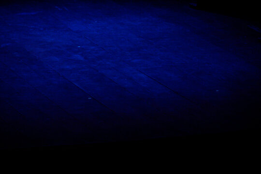 empty wooden stage illuminated by deep blue lighting, dark theater background with copy space, dramatic performing arts atmosphere concept