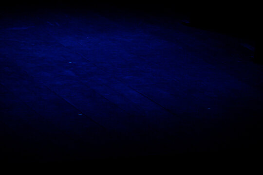 empty wooden stage illuminated by deep blue lighting, dark theater background with copy space, dramatic performing arts atmosphere concept