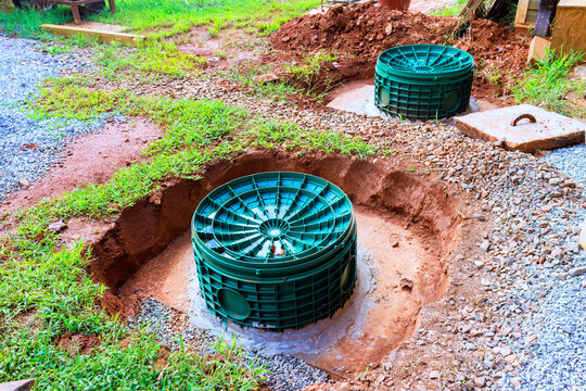Two circular green waste drainage tanks are placed in yard with soft soil layer of gravel around them.