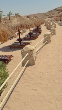 Tranquil beachfront loungers with straw parasols on sandy coastline Egypt. Hurghada