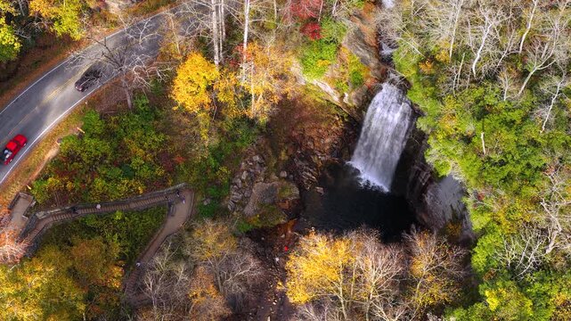Beautiful waterfall flowing through colorful autumn forest. Visitors enjoy panoramic views from observation platform above cascading stream.