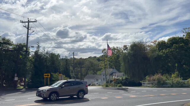 Cars driving through a road intersection with an American flag