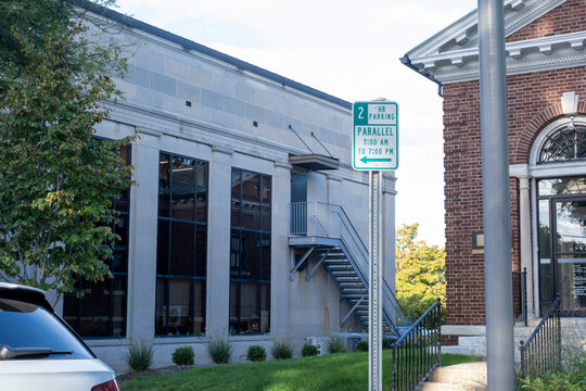 Parallel parking sign on post outside brick commercial building