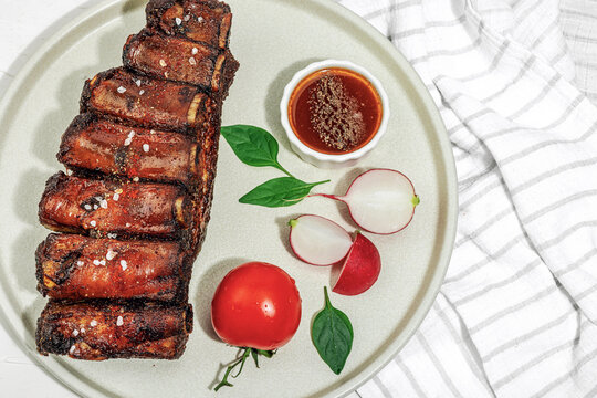 Baked pork ribs with spices, vegetables and sauce. Traditional ingredient for BBQ, picnic concept