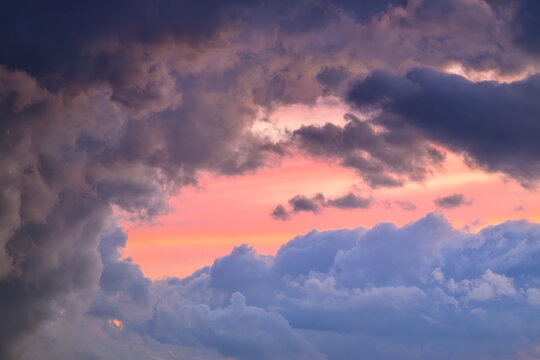 Dramatic sky with dark, heavy storm clouds breaking to reveal a vibrant, colorful sunset.