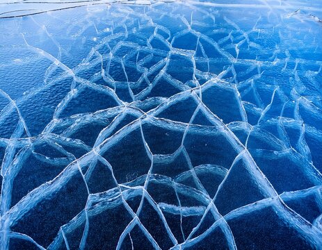 a cracked blue ice surface with intricate patterns possibly on a frozen lake or hockey rink