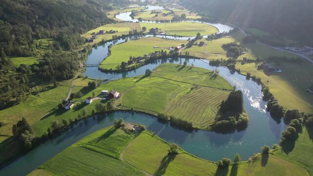 Curving river through green fields and meadows with isolated houses, aerial view, mountain valley with meandering Stryneelva River, Stryn, Vestland, Norway