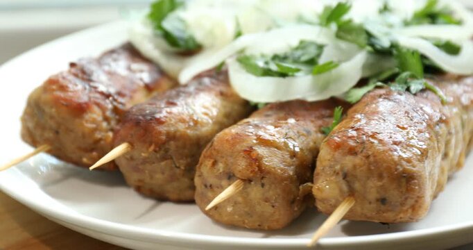 Tasty kebabs with parsley and onion on table, closeup