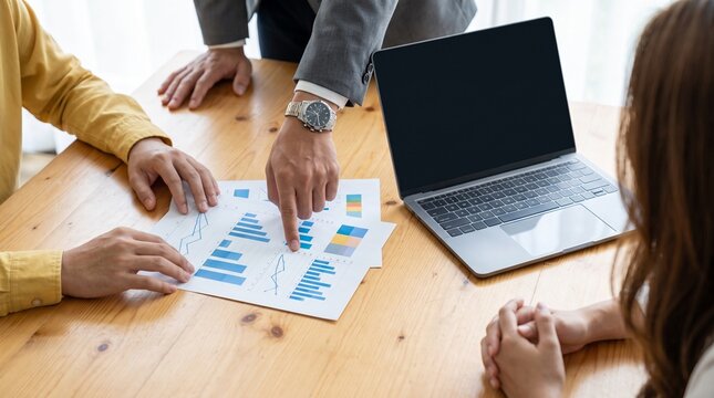 Business team analyzing financial charts on wooden table.